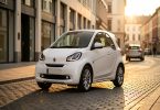 Citadine électrique blanche garée dans une rue de ville moderne au coucher du soleil