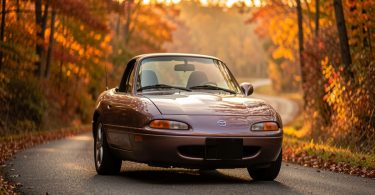 Mazda MX-5 NA classique sur une route de campagne au coucher du soleil, illustration pour guide collection automobile débutant