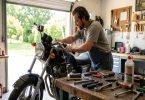 Mécanicien amateur faisant la vidange d une moto dans un garage, outils sur l établi