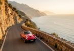 Voiture de collection rouge sur une route de montagne corse au coucher du soleil
