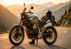 Motard vérifiant sa chaîne et ses pneus au bord d une route de montagne avant un road trip estival