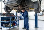 Mécanicien travaillant sous un véhicule levé dans un garage moderne avec outils professionnels