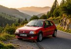 Peugeot 205 GTI rouge sur une route de montagne au coucher du soleil, voiture youngtimer qui monte a la cote